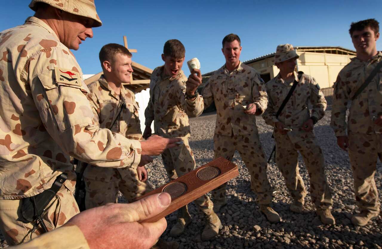 (File) Soldiers in Afghanistan enjoy a traditional Australian ANZAC Day game of two-up in 2009. (AAP)