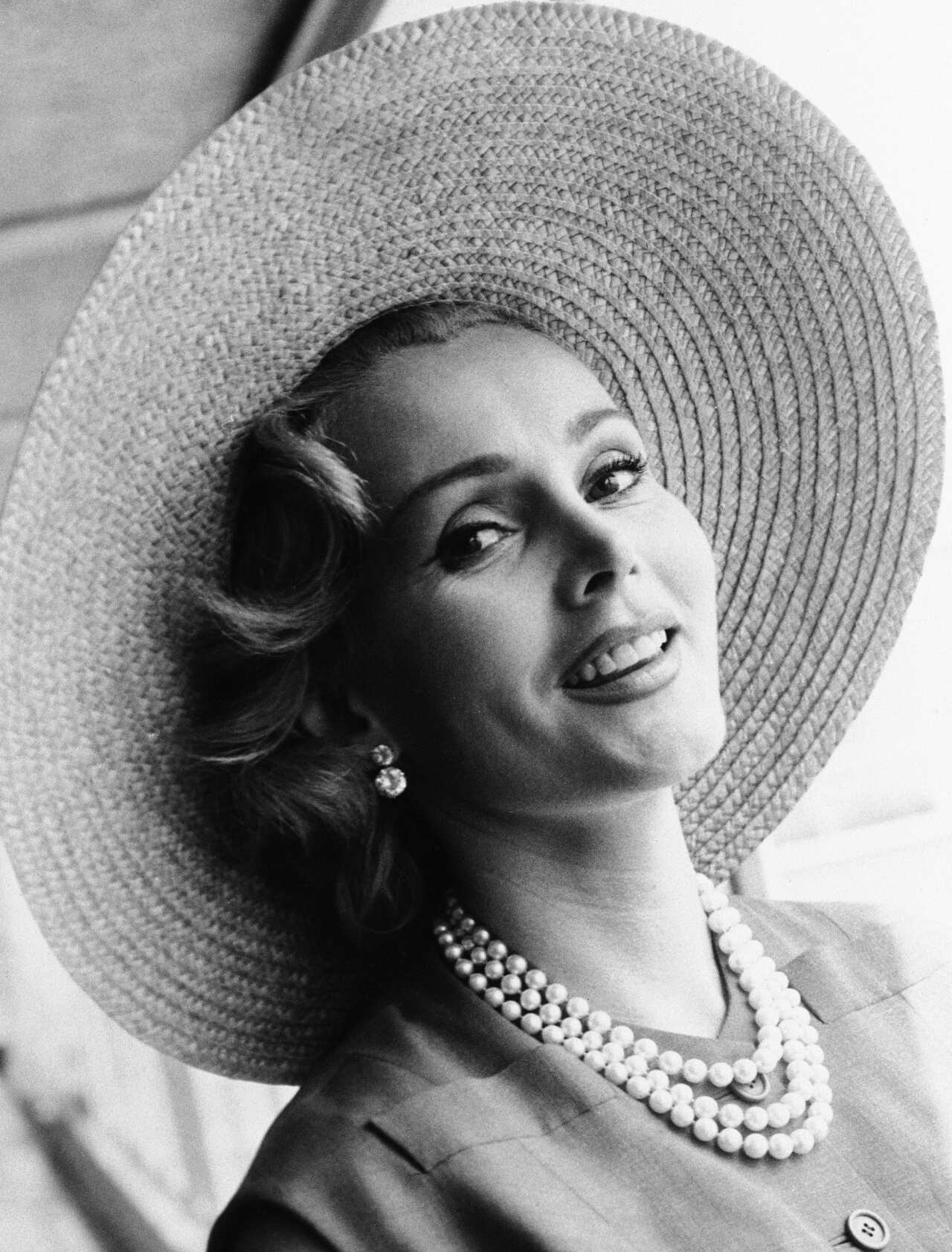 Zsa Zsa Gabor arrives at London Airport from Paris, in a Crimson dress and a straw hat on  July 14, 1955. (AP Photo)