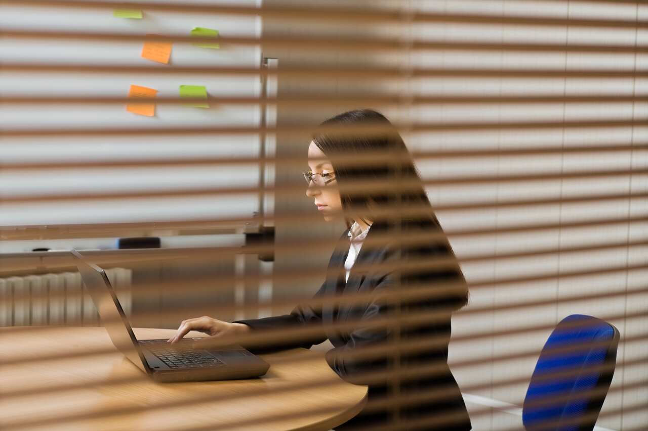 Woman working in office seen through blinds