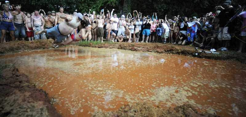 Robert "Robo" Sprague and his wife Rawni dive into a mud-filled pool during the 2011 Redneck Games.