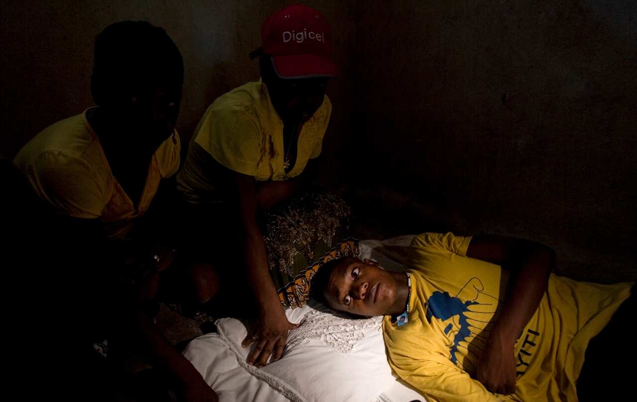 In this picture taken 2011, surrounded by relatives, an 18-year-old man who claims he was sexually abused by Uruguayan peacekeepers lies on his bed in Haiti.