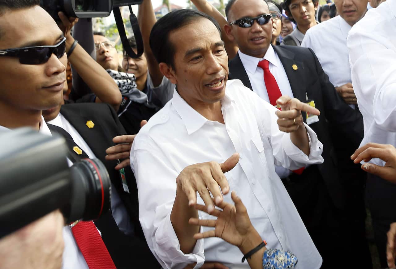 Governor of Jakarta, Joko Widodo (C) is greeted by residents during his visit at a residential area in Jakarta, Indonesia. (AAP)