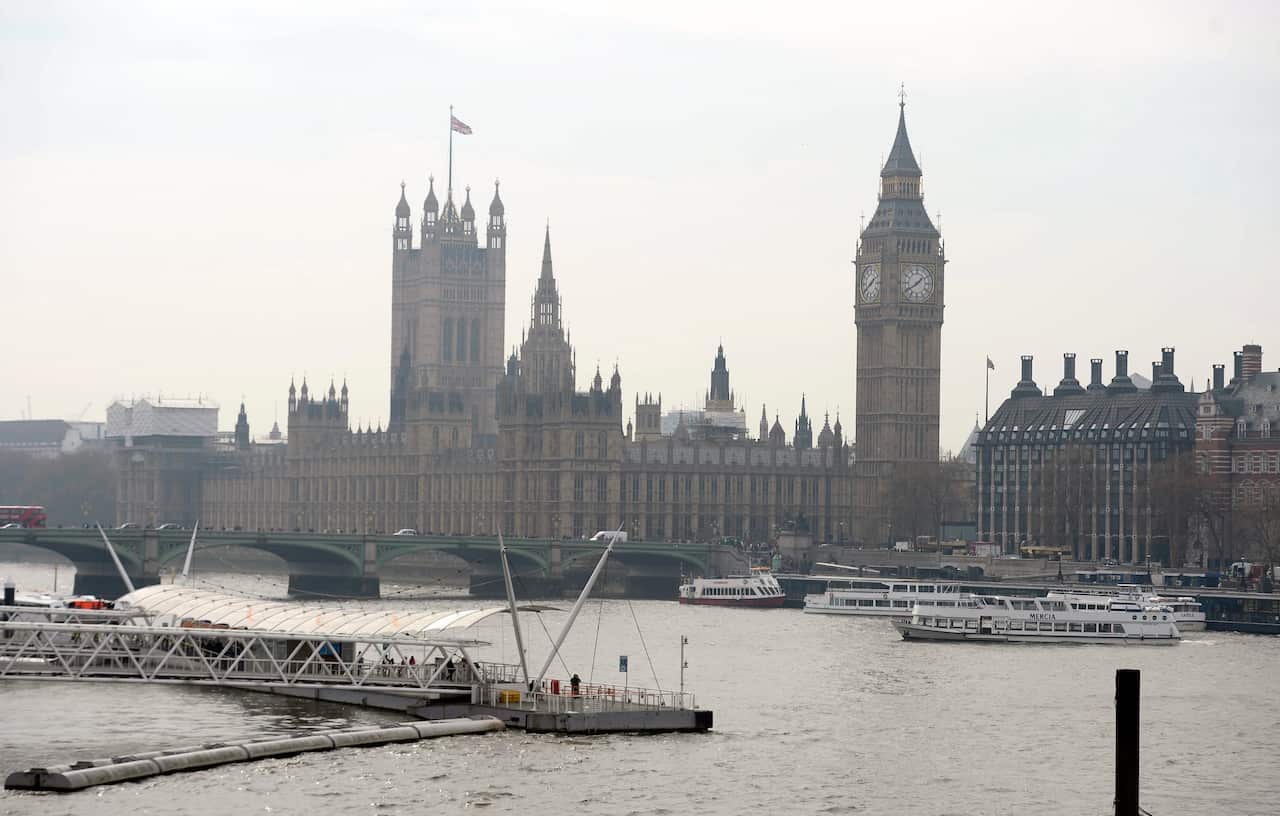 London's Parliament House stands behind the River Thames, partially shrouded in smoke.