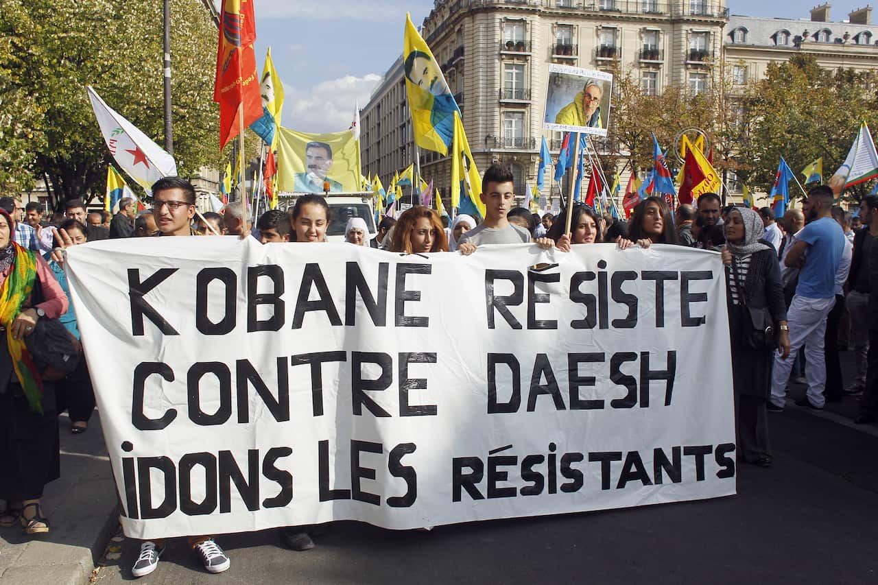 Kurdish people hold a banner reading 'Kobane resists against Islamic State, help resistance' during a rally in Paris against the threat of genocide by Islamic State militants. (AFP)