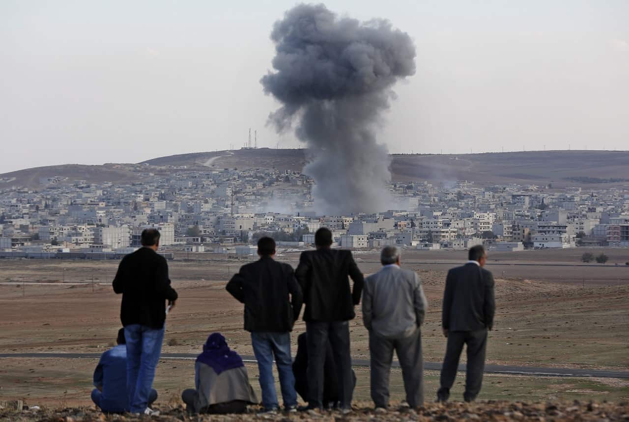 Residents watch smoke from an explosion rising over the Syrian city of Kobane in 2014.