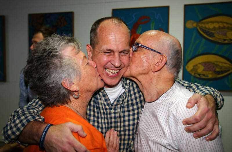 Australian journalist Peter Greste is hugged by his mother Lois, left, and father Juris, right, after his arrival in Brisbane.