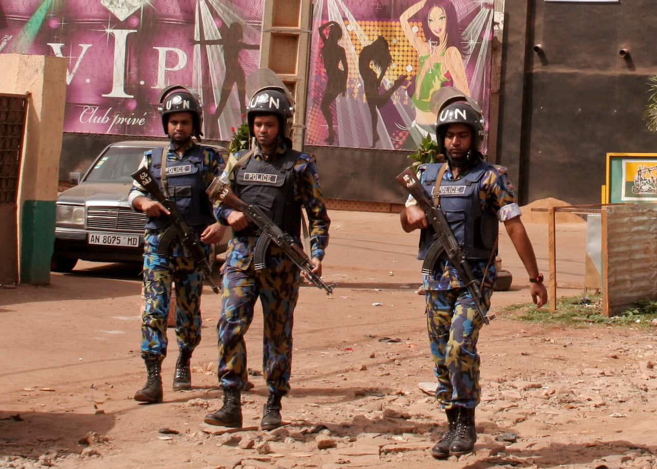 FILE - In this file photo taken on Saturday, March 7, 2015,  armed forces provide security  for the nightclub, seen rear, that was attacked by gunmen  in Bamako, Mali. A new report says that armed groups in Mali are carrying out a growing number of attack