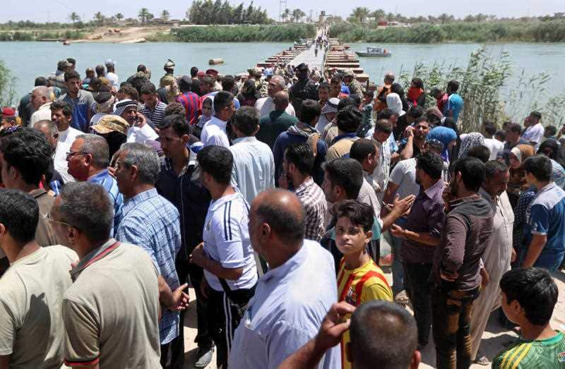 Displaced Iraqis from Ramadi gather at the Bzebiz bridge after spending the night walking towards Baghdad, as they flee their hometown, 65 km west of Baghdad, Iraq, Saturday, May 16, 2015. (AAP)