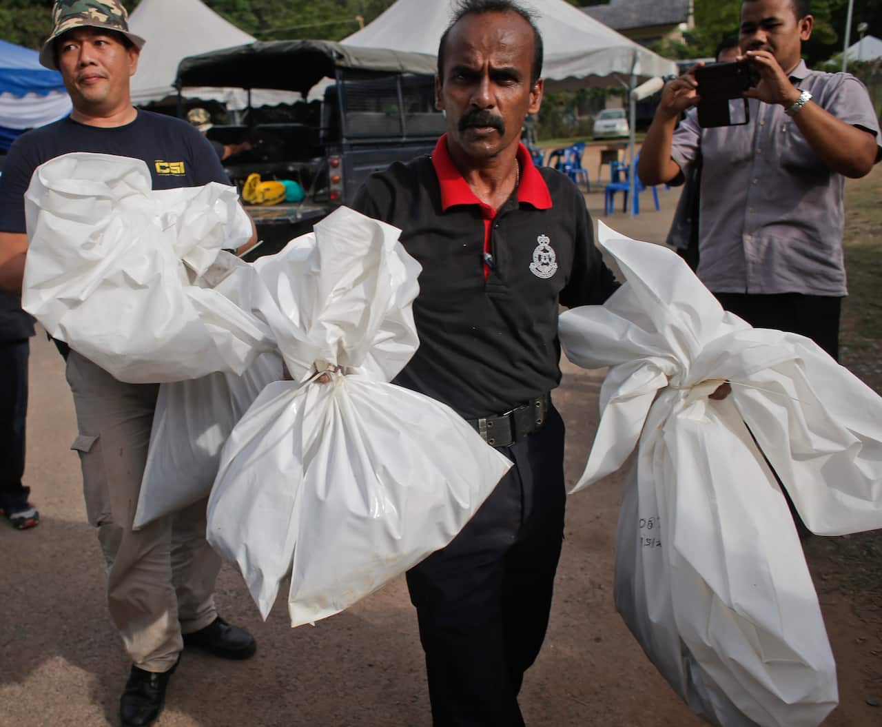 A Malaysian policeman carries bags with human remains at Wang Kelian, Perlis, Malaysia, 25 May 2015