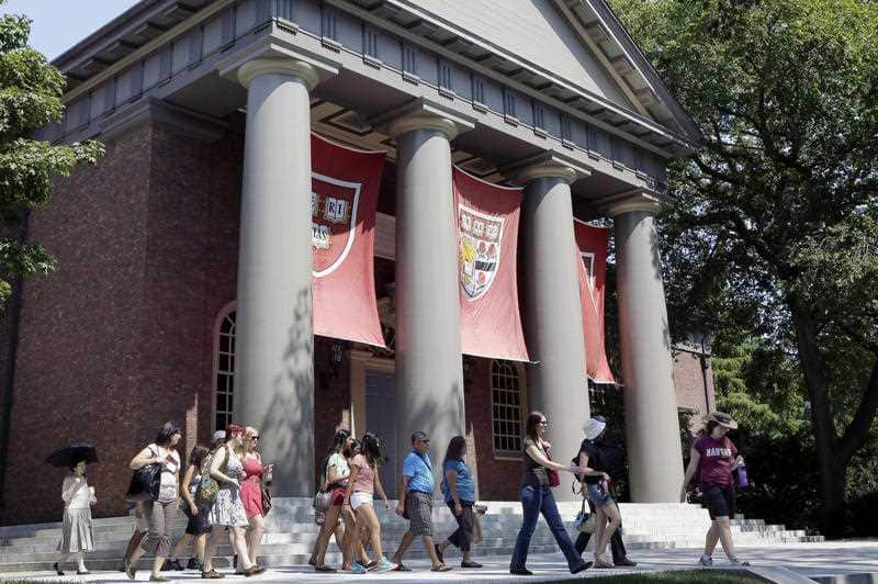 A tour group walks through the campus of Harvard University.