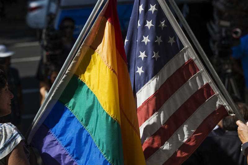 A rainbow flag and a US flag are displayed together on the steps of the Sacramento LGBT Community Center in 2015.