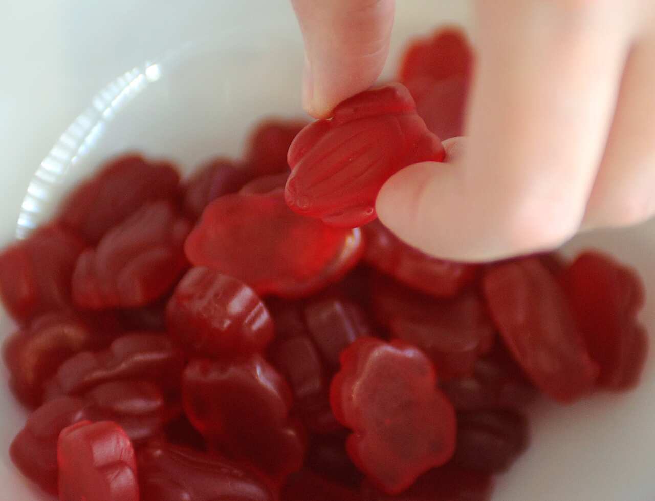 A woman takes a Red Frog lolly from a bowl, Sydney, Tuesday, June 30, 2015. Lolly maker Allen's announced it's dumping the Green Frogs along with Spearmint Leaves because of poor sales. (AAP Image) NO ARCHIVING