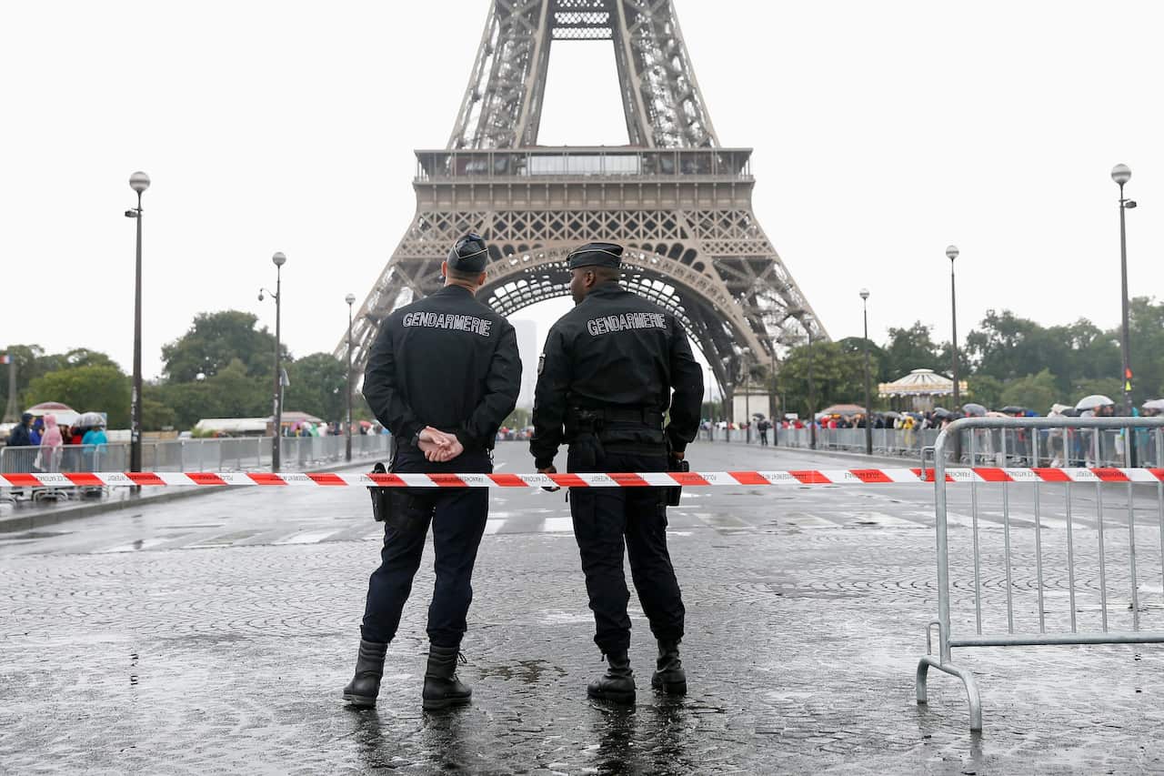 Two French police officers stand guarding the bridge in front of the Eiffel Tower prior to the arrival of the 2015 Tour de France in Paris