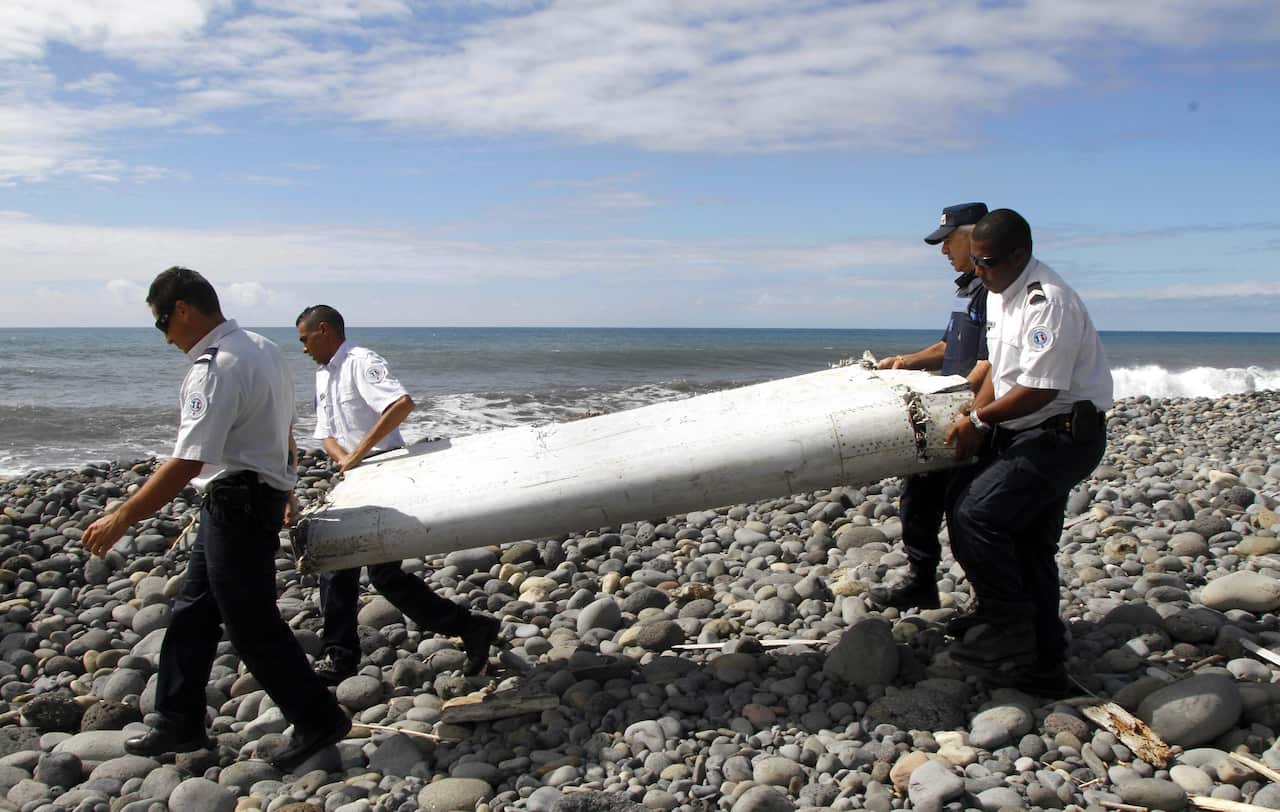 Officers carry the flaperon found washed ashore in Saint-Andre de la Reunion, eastern La Reunion island, France. 