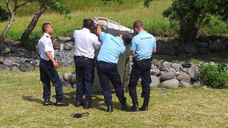 Members of French Gendarmerie and local authorities checking a piece of debris from an aircraft washed ashore in Saint-Andre de la Reunion, eastern La Reunion island, France. (AAP)