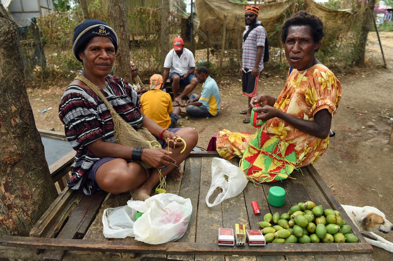 Two women sell betel nuts at a roadside stall near Port Moresby.