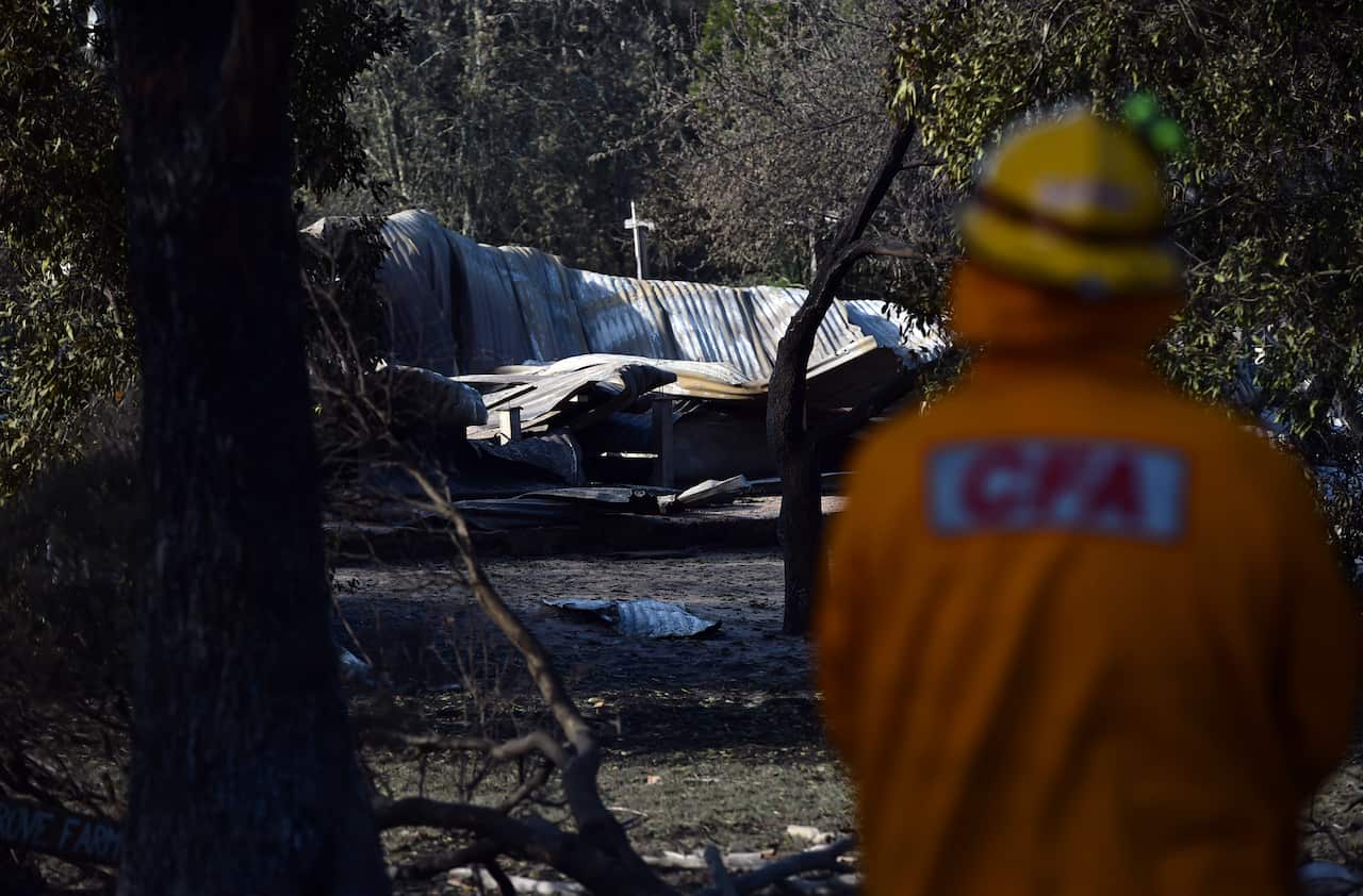 A CFA firefighter surveys the ruins of a house near Lancefield north of Melbourne