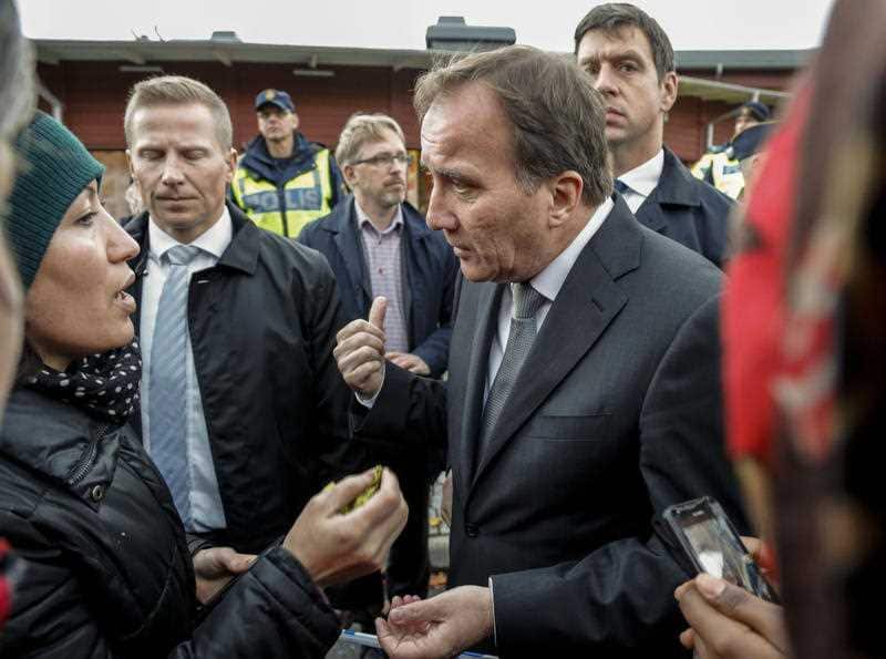 Prime Minister Stefan Lofven, right, talks to local people near the school Thursday afternoon where a masked man wielding what looked like a sword stabbed four people Thursday Oct. 22, 2015, in Trollhattan, Southern Sweden. 