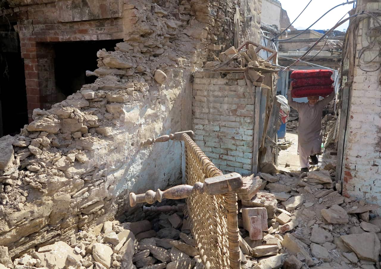  A man removes his belongings from a house damaged by massive earthquake in Mingora, the main town of Swat valley.