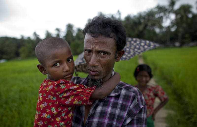 A Rohingya man, who was displaced following 2012 sectarian violence, carries his daughter at Nga Chaung refugee camp in Pauktaw, western Rakhine state, Myanmar.