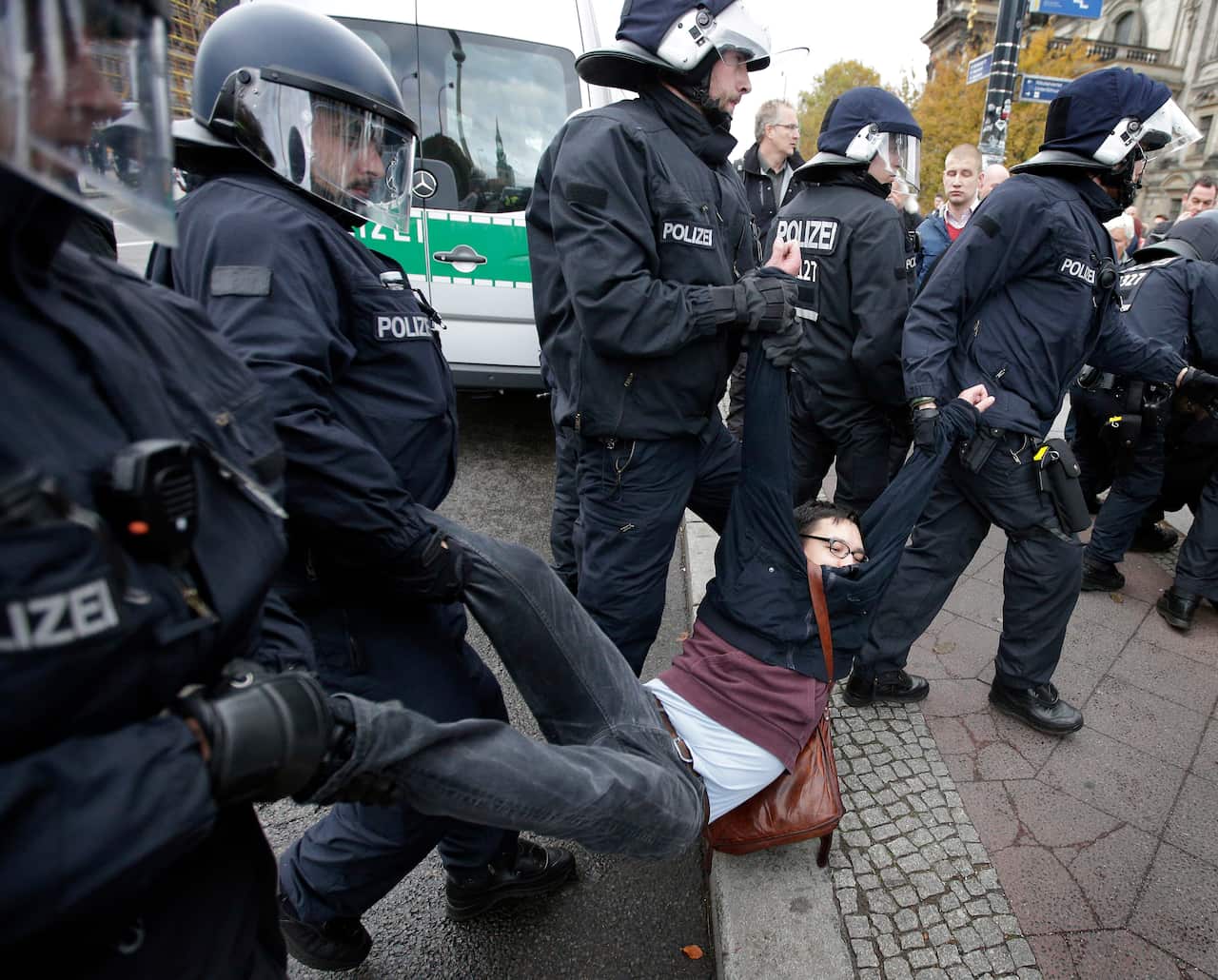 Police officers carry away people who try to stop a protest rally of the German party 'Alternative fuer Deutschland, AfD' (Alternative for Germany) in Berlin