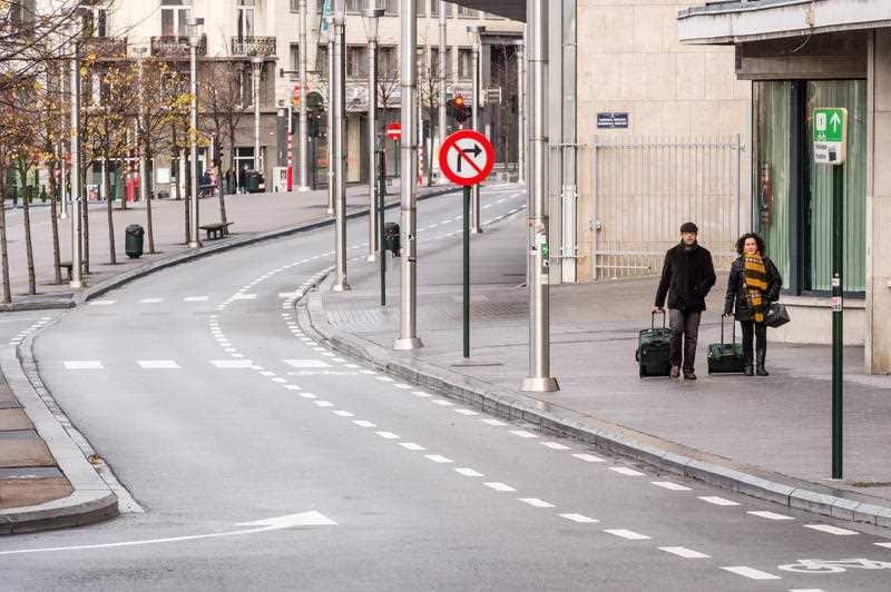 Two tourists walk in a deserted street towards the main train station in the center of Brussels on Sunday, Nov. 22, 2015. 