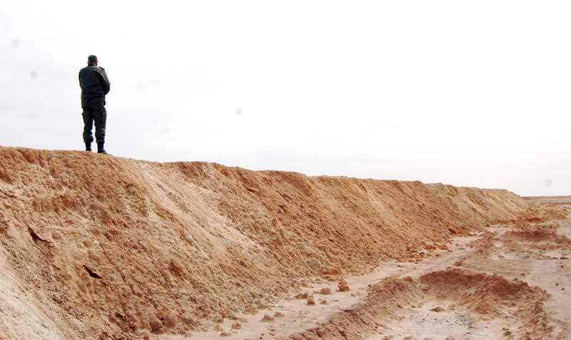 A Tunisian soldier stands on a sandbank during a presentation of the anti-jihadi fence, in near Ben Guerdane, eastern Tunisia, close to the border with Libya, Saturday, Feb. 6, 2016.