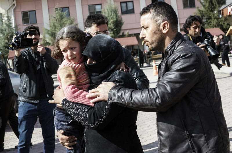 A Turkish man helps a Syrian woman carrying a wounded Syrian girl to a hospital in Kilis, Turkey, Monday, Feb. 15, 2016. 