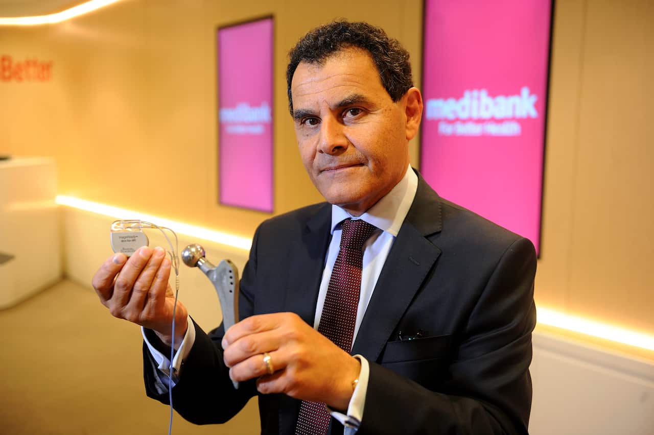 Medibank Private CEO George Savvides holds a hip replacement part, during the company's half year results, on Friday, Feb. 19, 2016. Medibank Private said its first-half net profit rose 58.3 per cent to $227.6 million. (AAP Image/Joe Castro) NO ARCHIVING