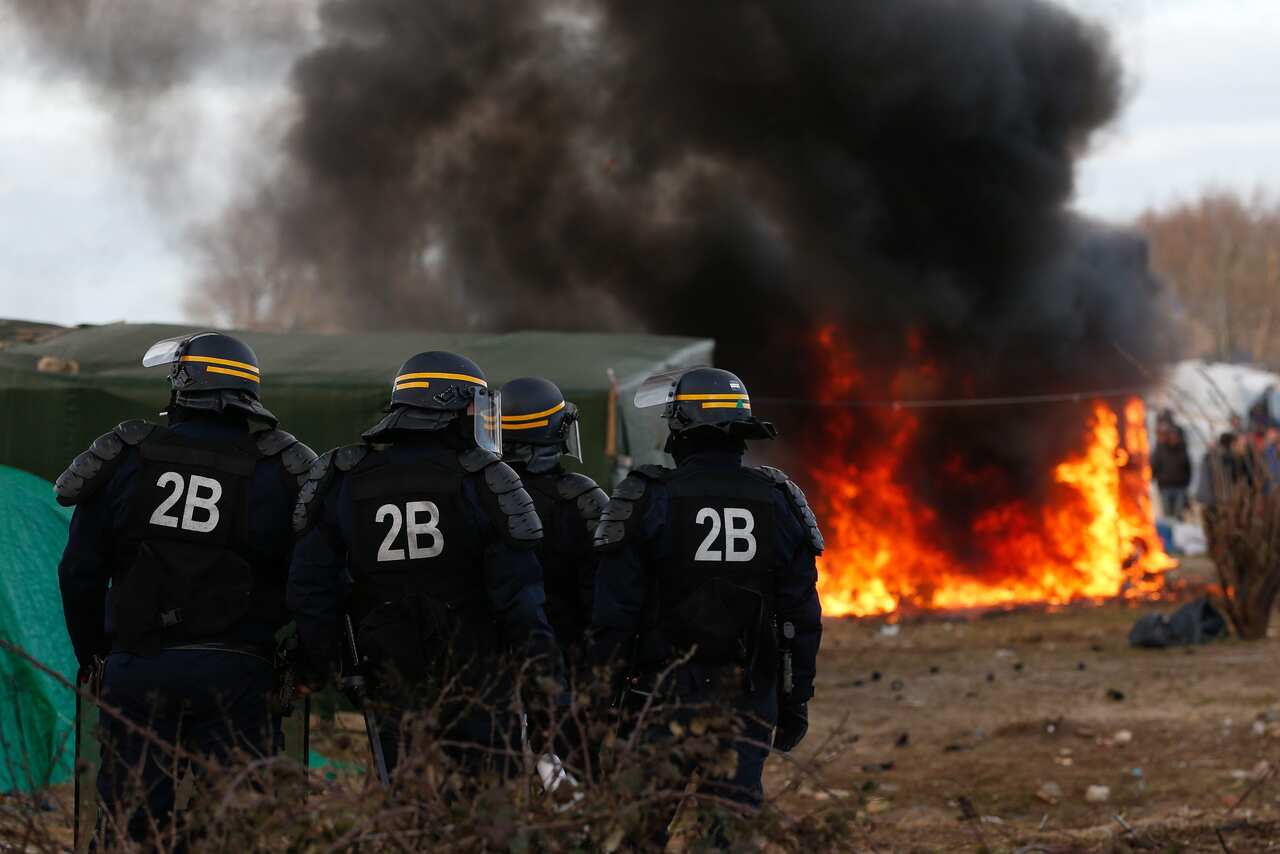 French riot police infront of a burning shelter at the start of the demolition of a part of the Jungle migrant camp in Calais, France, 29 February 2016. 