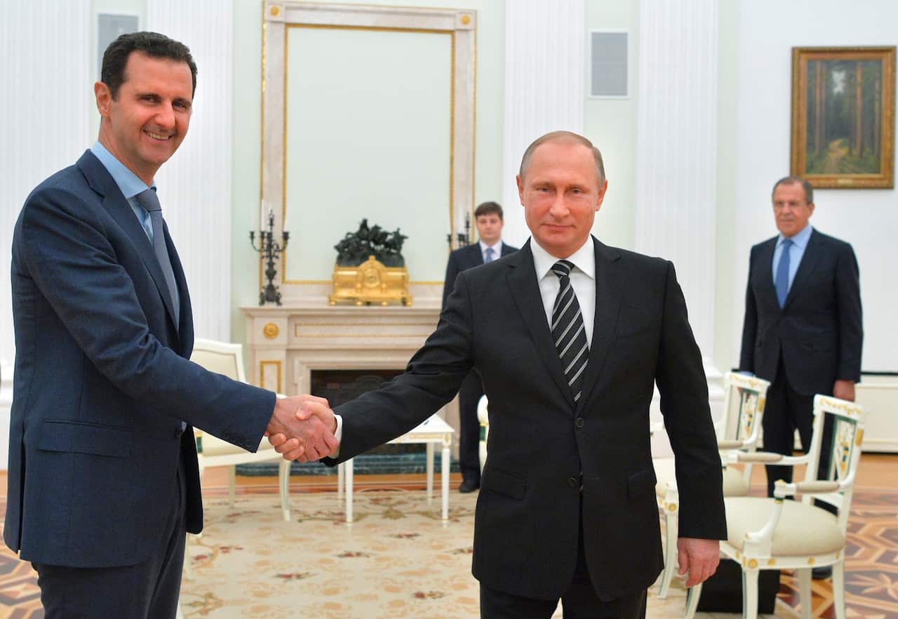 Bashar al-Assad shaking hands with Russian President Vladimir Putin (AP)
