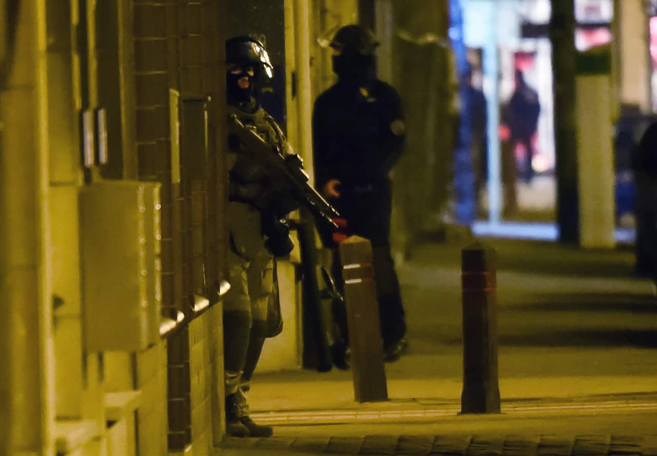 A special police officer stands in a doorway during an apartment raid in Brussels on Tuesday March 15, 2016.
