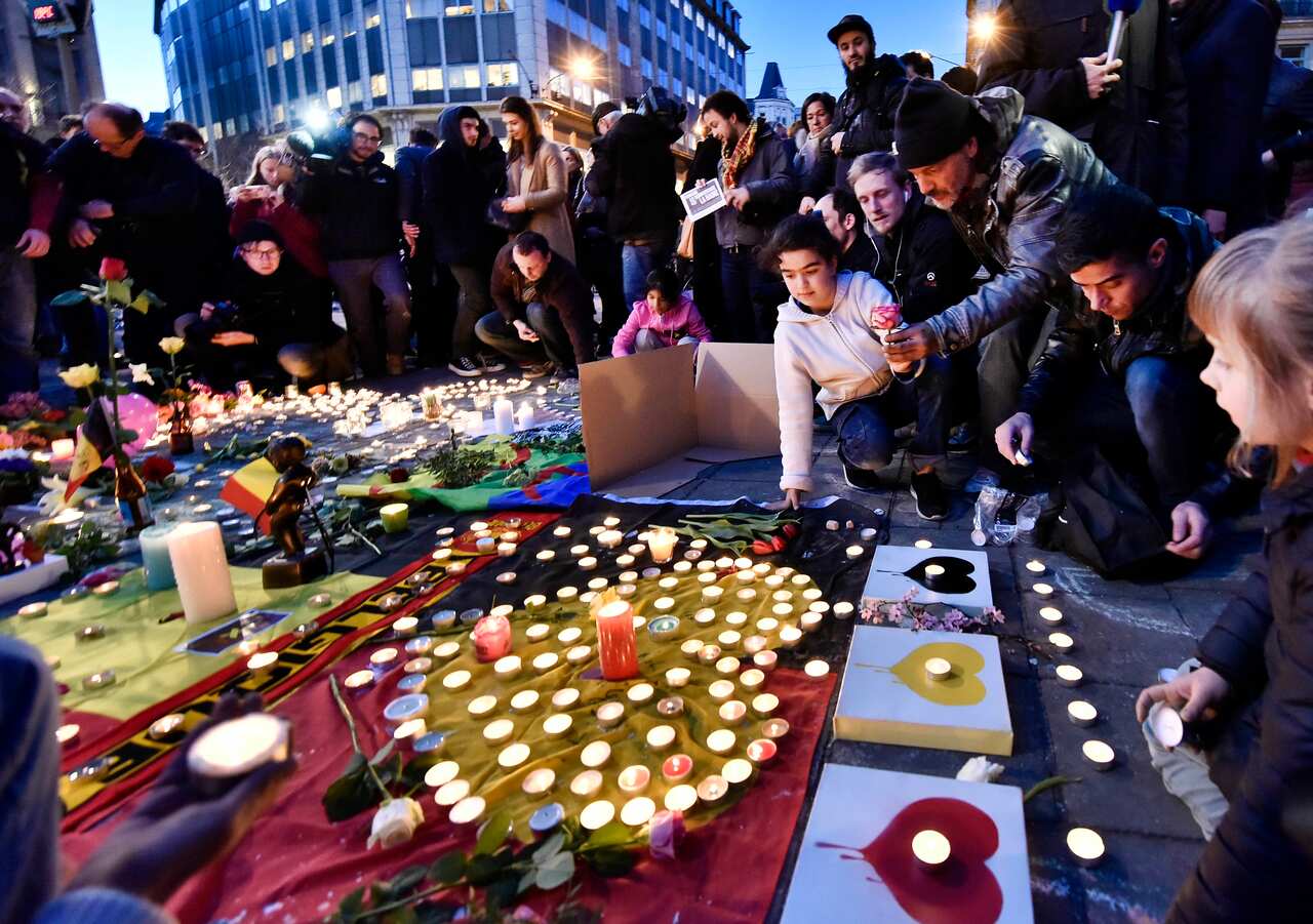 People bring flowers and candles to mourn for the victims at Place de la Bourse in the center of Brussels.