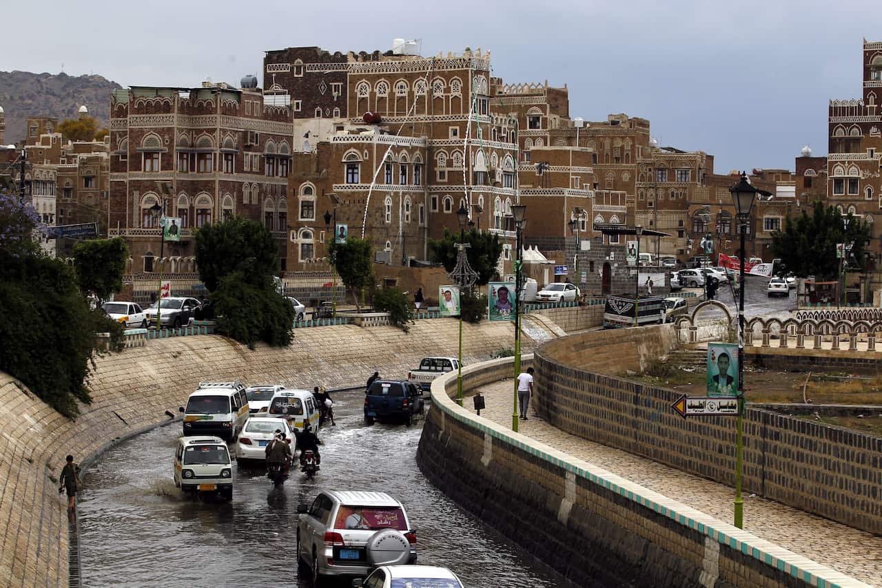 Vehicles drive on a flooded street in front of historic buildings in rainy day at a market ahead of a UN-announced ceasefire in the old city of Sana'a. (EPA)