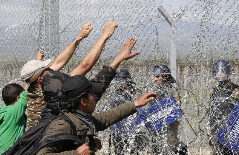 File image of a group of migrant men attempt to tear apart the fence during a protest at the northern Greek border point of Idomeni, Greece.