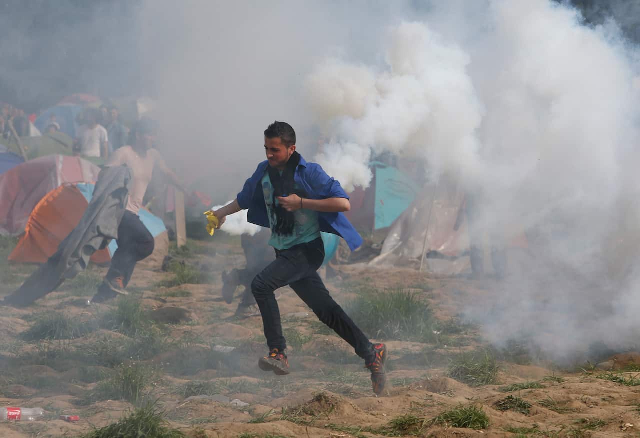 A migrant man with a tear gas canister during clashes with Macedonian police during a protest at a fence at the northern Greek border point of Idomeni