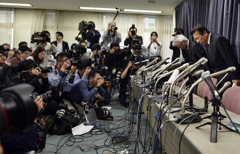 Mitsubishi Motors Corp's President Tetsuro Aikawa (right) bows at the start of a press conference regarding irregular fuel efficiency tests by the carmaker.