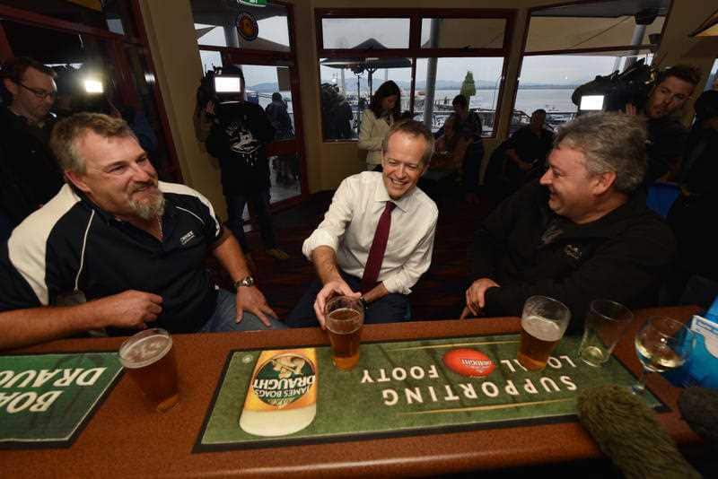 Three men laughing and drinking beer at a pub.