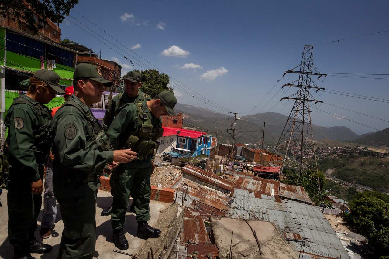 Members of the Armed forces look out over a a western district in Caracas.
