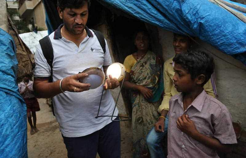 Raghavendra Bugade of Pollinate Energy holds lithium battery run solar lights as he interacts with the slum dwellers in Bangalore, India.