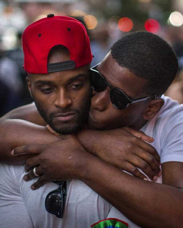 A couple hug and kiss in front of a makeshift memorial to remember the victims of a mass shooting in Orlando, Fla., in New York, Sunday, June 12, 2016.
