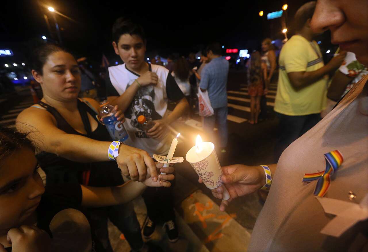 A woman lights a candle with two younger children.
