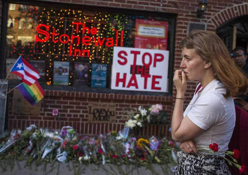  A woman cries and holds flowers in front of a makeshift memorial to remember the victims of a mass shooting in Orlando, Fla., in New York, Sunday, June 12