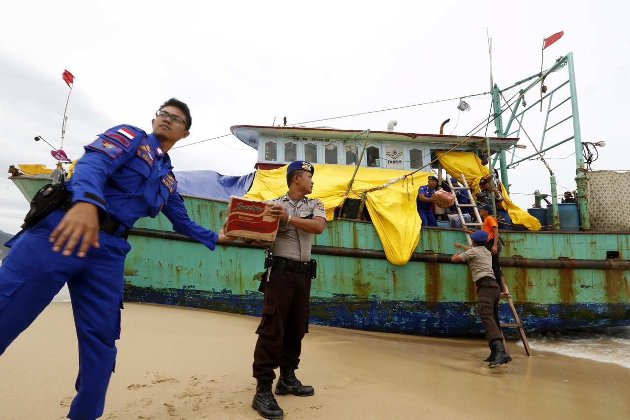 Indonesian police officers load food for Sri Lankan migrants into their boat at Lhoknga Beach, Aceh, Indonesia