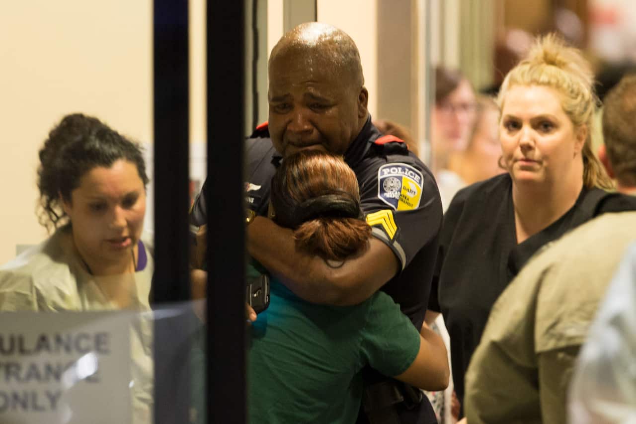 A Dallas Area Rapid Transit police officer receives comfort at the Baylor University Hospital emergency room entrance