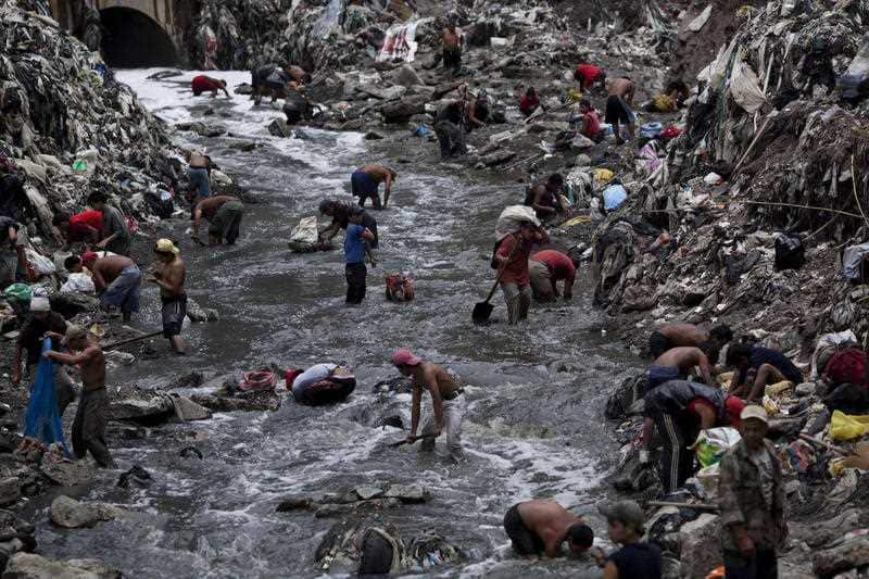 Poverty stricken: 2011 file photo, people search for scrap metal in contaminated water at the bottom of one of the biggest trash dumps in Guatemala city.