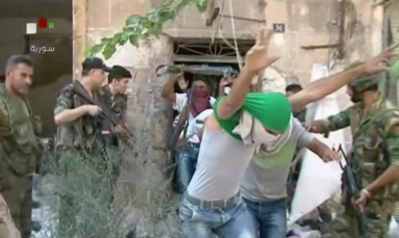 This still image from Syrian state TV video, shows young men with their faces covered surrendering to government forces, in Aleppo, Syria