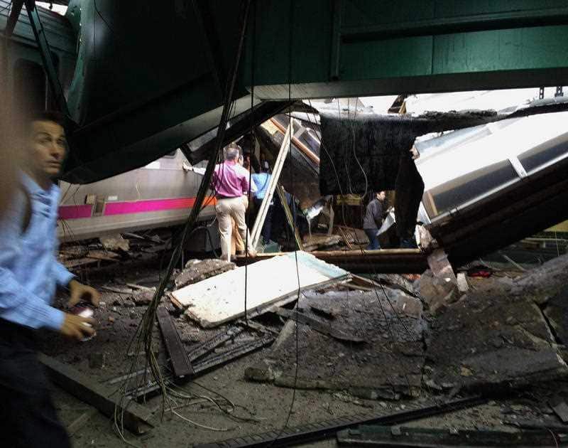 People examine the wreckage of a New Jersey Transit commuter train that crashed into the train station during the morning rush hour in Hoboken.