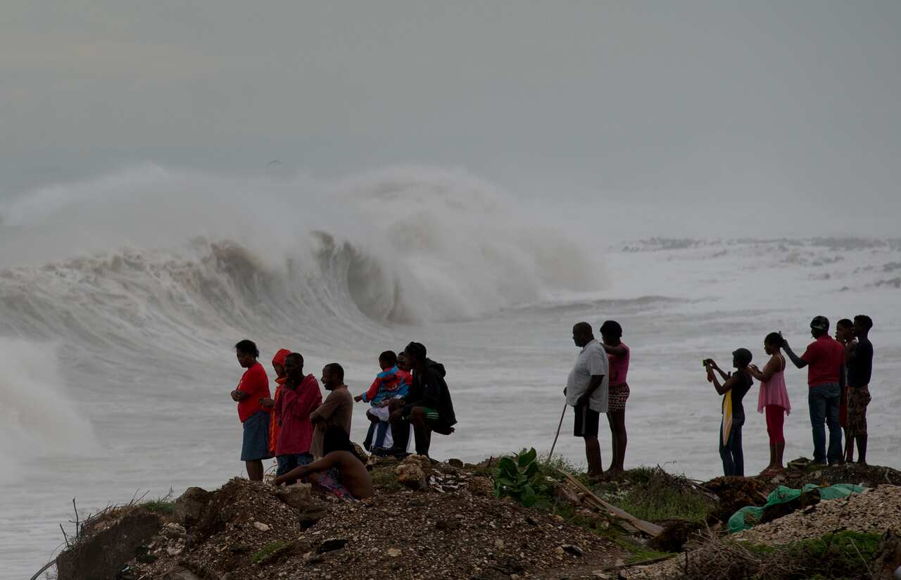 People stand on the coast watching the surf produced by Hurricane Matthew, on the outskirts of Kingston, Jamaica, Monday, Oct. 3, 2016.