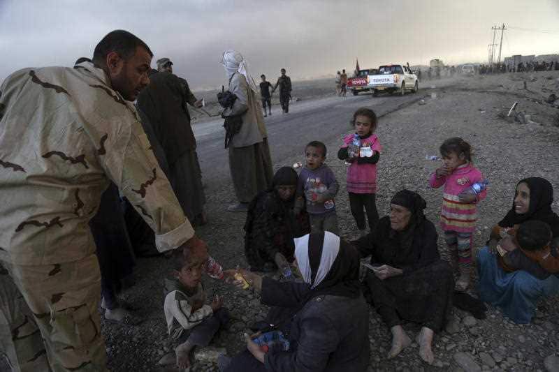 People rest as they flee their homes during clashes between Iraqi security forces and members of the Islamic State group fleeing Mosul, Iraq, Tuesday, Oct. 18, 
